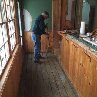 A man is sweeping the floor of a room with a broom.