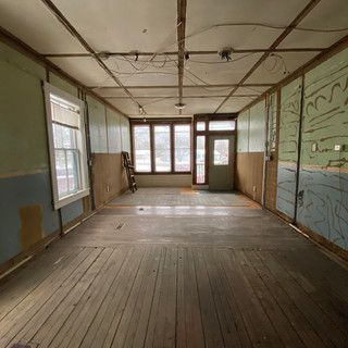 A large empty room with wooden floors and a door.