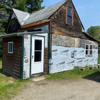 A small wooden house with a white door and windows is being remodeled.