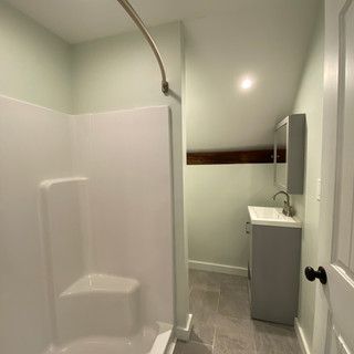 A bathroom with a shower , sink and mirror.