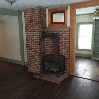 A living room with a brick fireplace and a wood stove