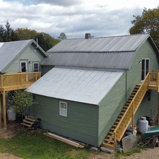 A green house with stairs leading up to it and a wooden deck.