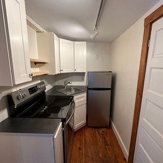 A kitchen with a stove , refrigerator , sink and cabinets.