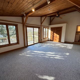 An empty living room with a lot of windows and a ceiling fan.