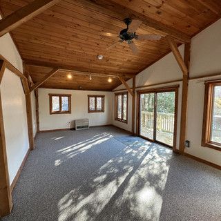 A large empty room with a wooden ceiling and a ceiling fan.