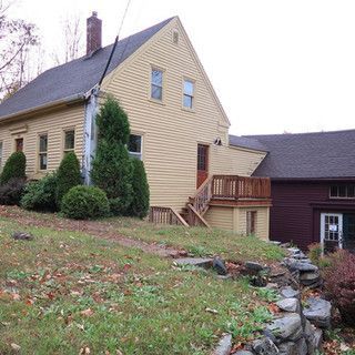 A large house sits on top of a grassy hill