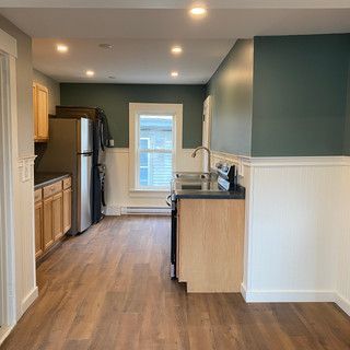 A kitchen with hardwood floors , stainless steel appliances , and a refrigerator.