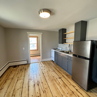 A kitchen with wooden floors and a stainless steel refrigerator