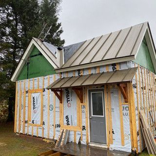 A small house is being built with a metal roof and a porch.