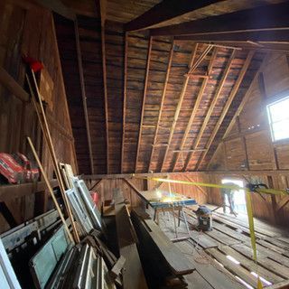 The inside of a wooden barn with a lot of wood and tools.