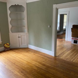 An empty living room with hardwood floors and a bookshelf.