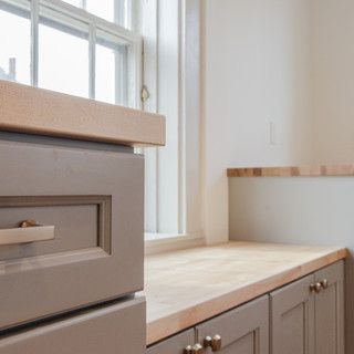 A kitchen with gray cabinets and a wooden counter top