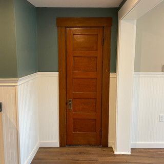 A hallway with a wooden door and white trim.