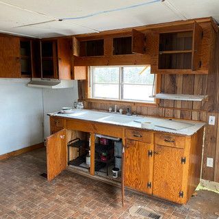 A kitchen with wooden cabinets , a sink , and a window.
