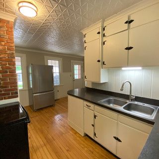 A kitchen with white cabinets , a sink , a refrigerator and a stove.