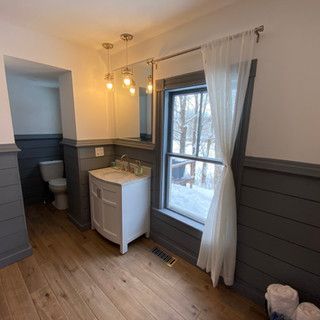 A bathroom with a sink , toilet , mirror and window.