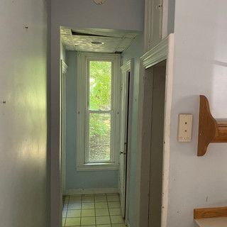 A hallway in a house with a window and tile floor.