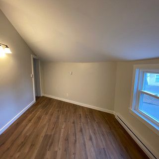 An empty room with hardwood floors and a window.