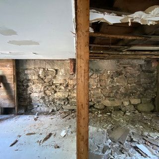 A room with a stone wall and a wooden post in it.