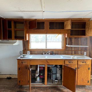A kitchen with wooden cabinets , a sink , and a window.