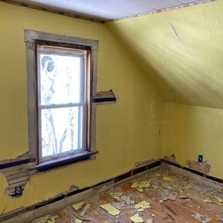 An empty room with yellow walls and a window.
