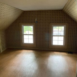 An empty room with a vaulted ceiling and two windows.