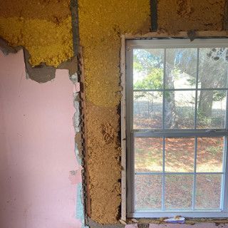 A room with a window and a wall that is being remodeled.