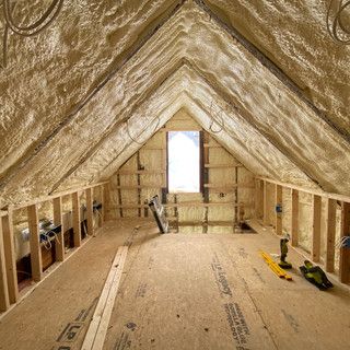 An attic with a lot of insulation and a window.