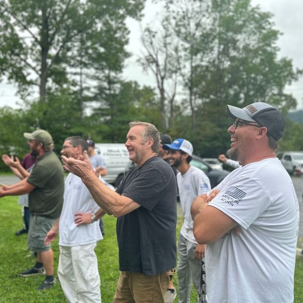 A group of men are standing in a grassy field.