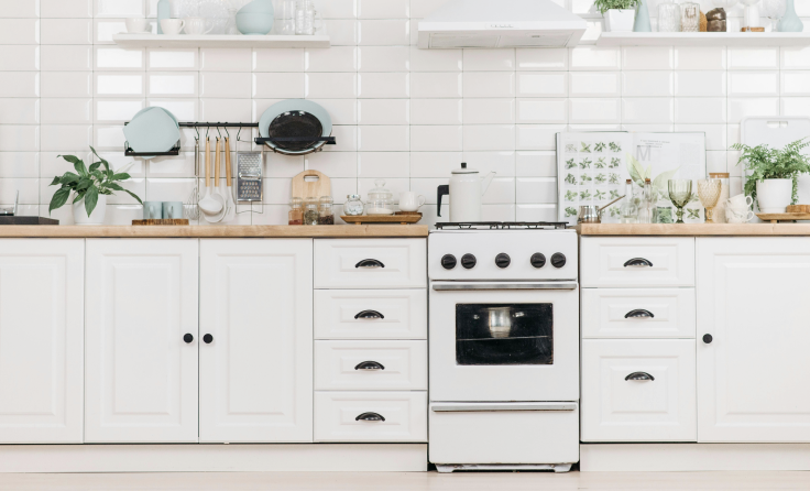 A kitchen with white cabinets, a stove, and a sink.