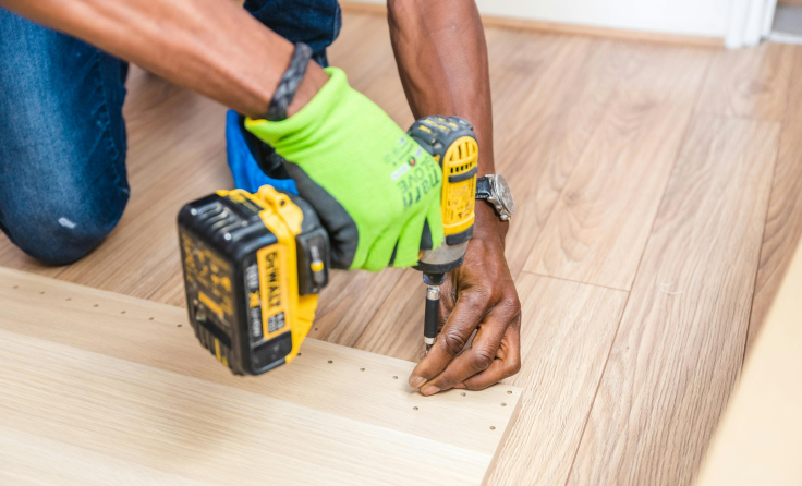 A man is using a drill to drill a hole in a piece of wood.