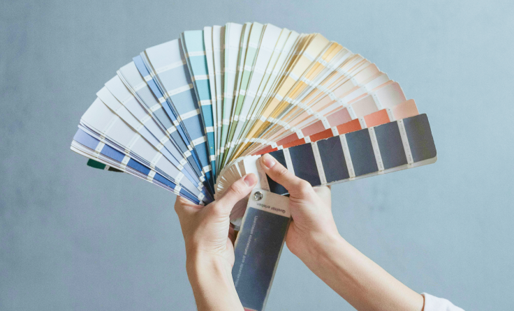 A person is holding a fan of paint samples in their hands.