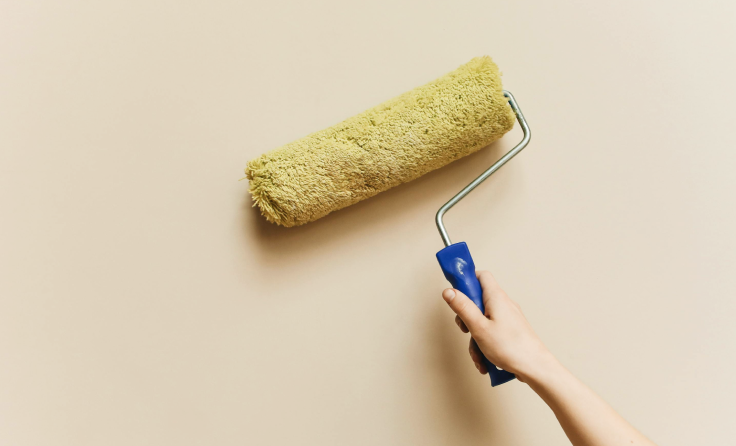 A person is painting a wall with a paint roller.