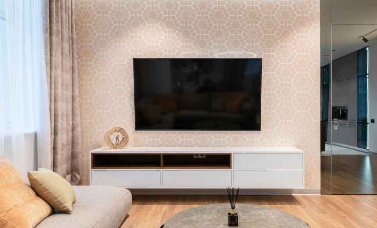 A living room with a couch and a flat screen tv on the wall.