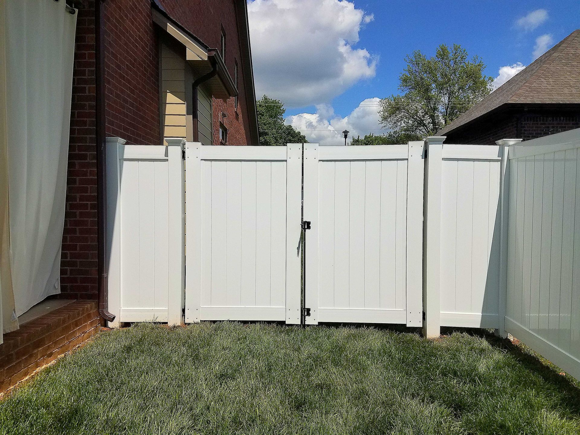 White picket fence with gate in front of a brick building.