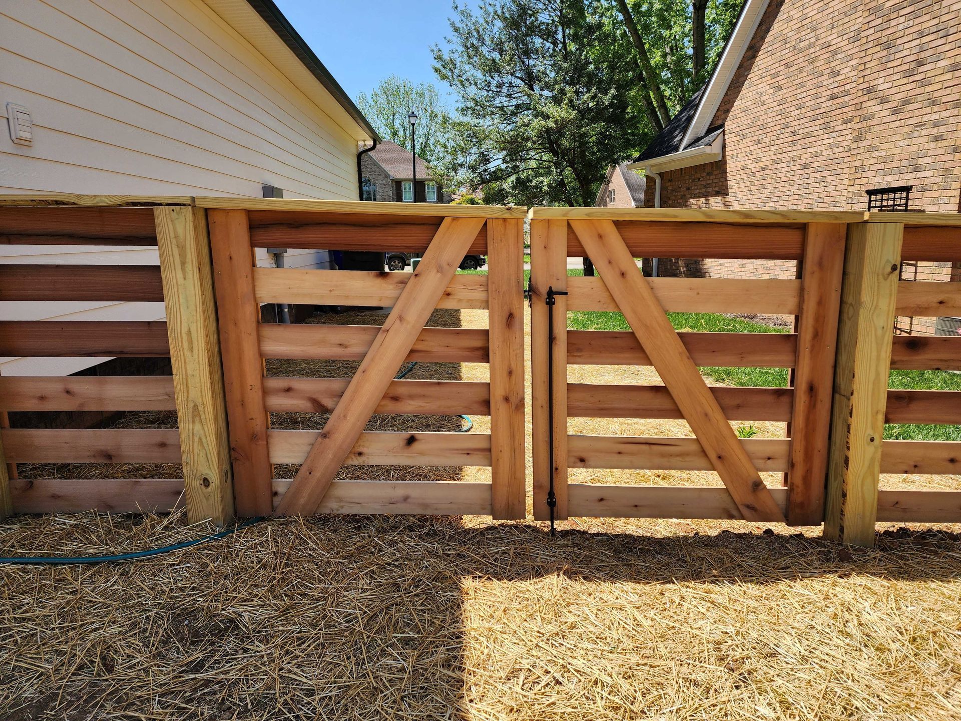 Wooden gate and fence made from repurposed materials in a backyard setting.