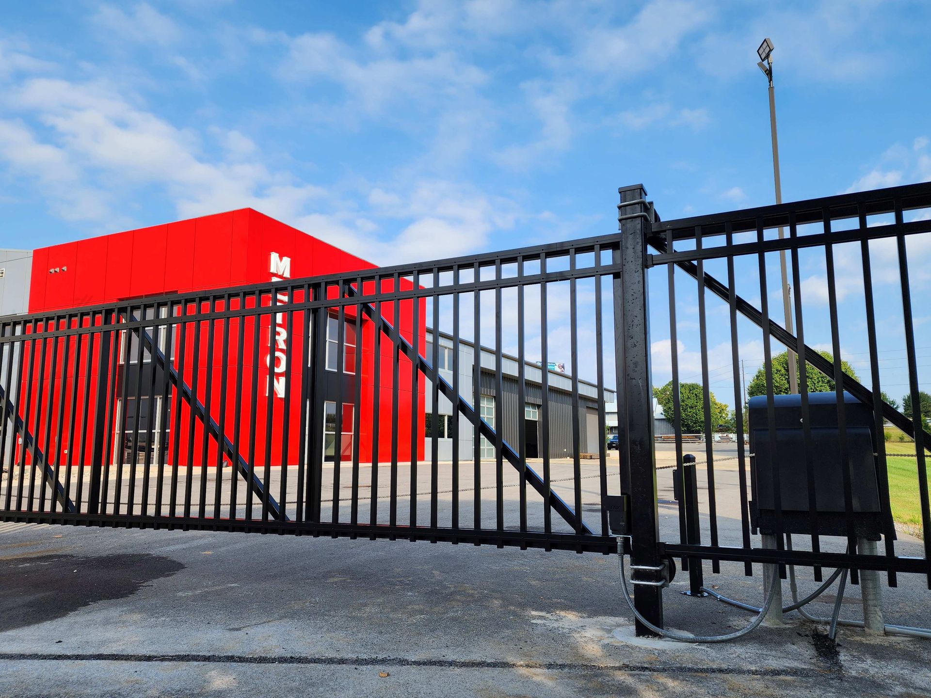 Black metal security gate with a red building and blue sky.