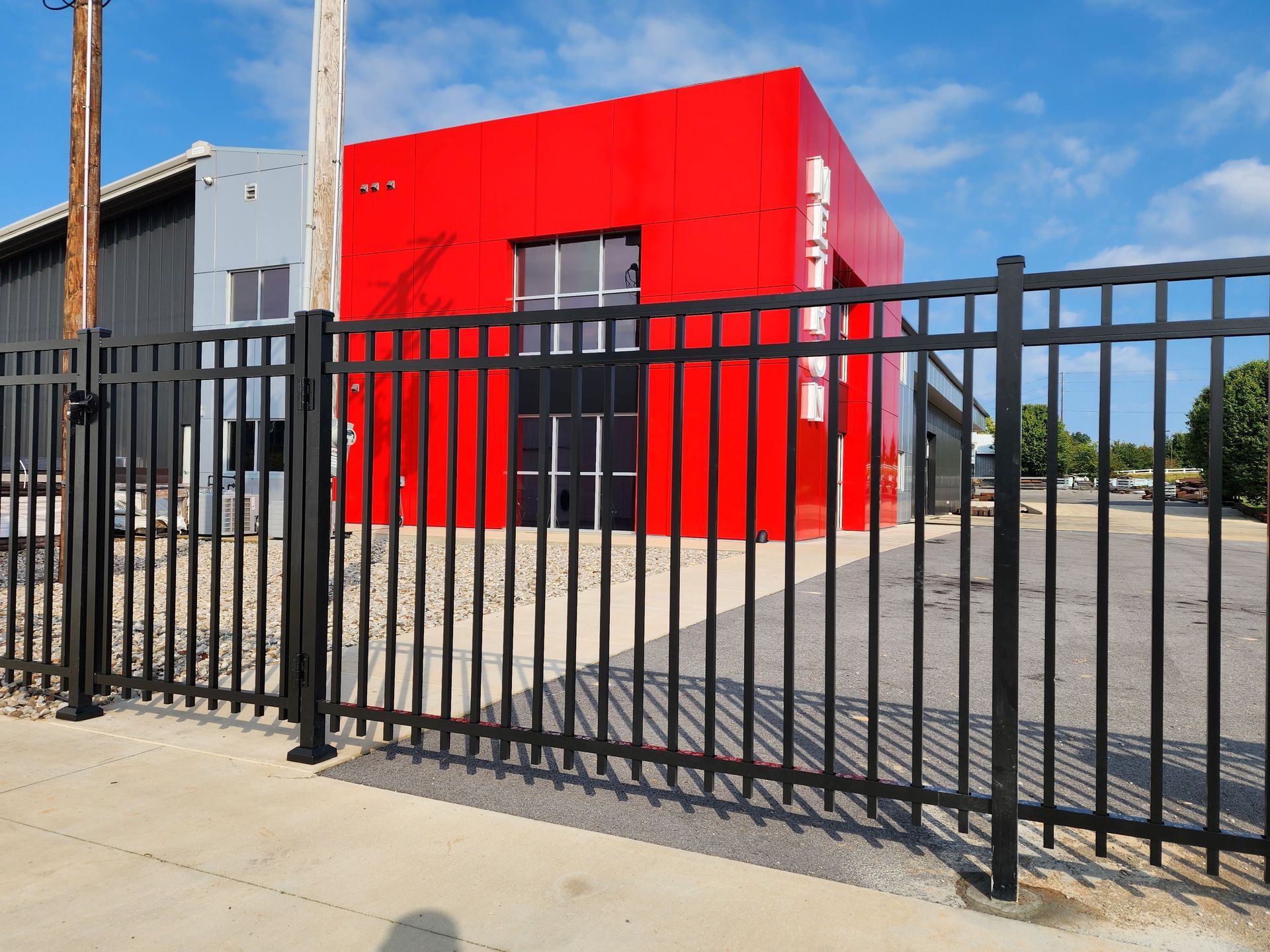 Black metal fence in front of a vibrant red building with a black door.