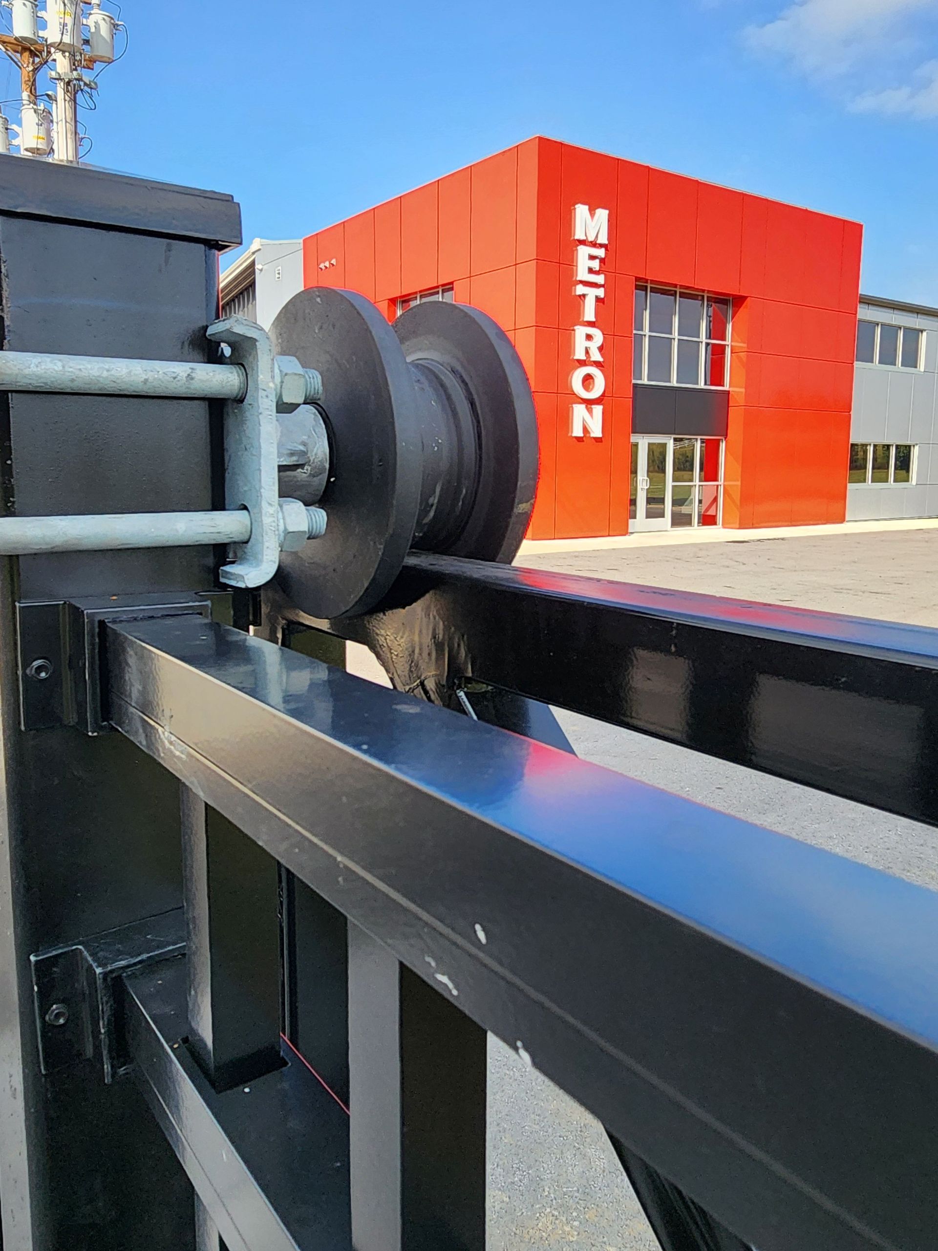 Black gate with pulley system in front of a red building with 