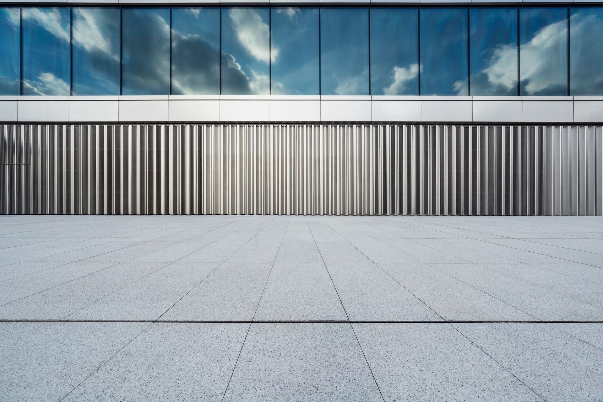 A large building with a lot of windows and a concrete floor in front of it.