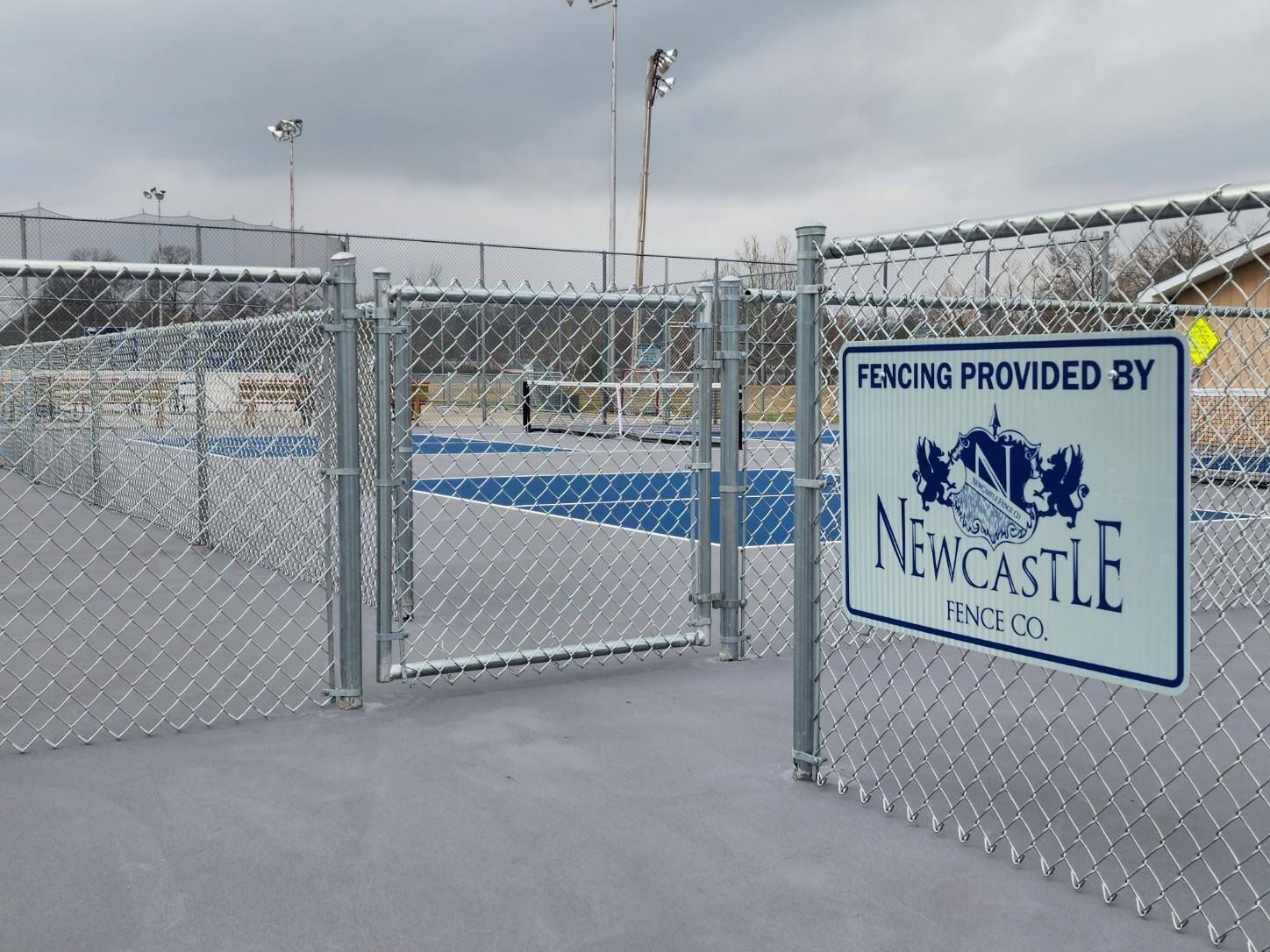 Tennis court behind a chain link fence with a sign that reads 