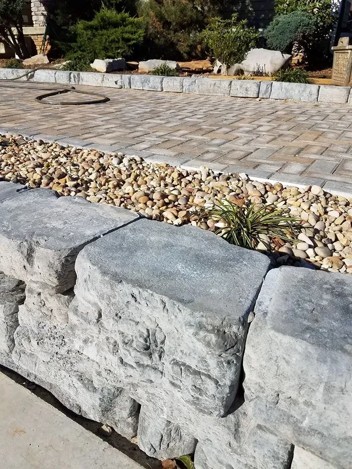 A stone wall surrounded by gravel and bricks in a garden.