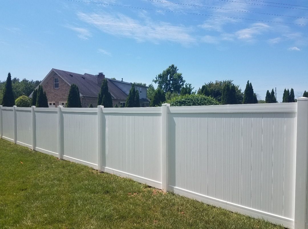 White vinyl fence in front of a house on a sunny day.