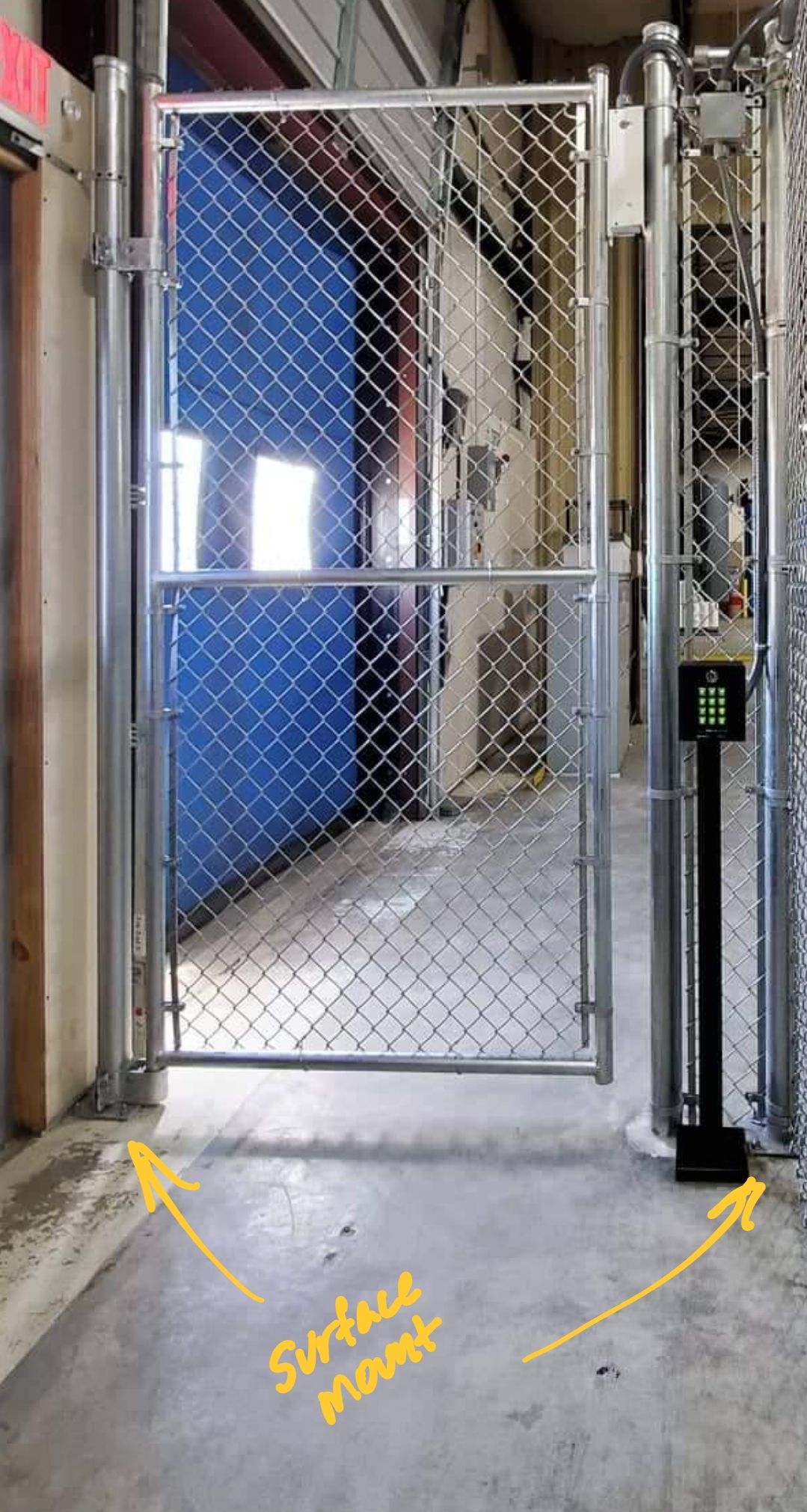 Chain-link security gate with a surface-mounted keypad and reader on a concrete walkway.