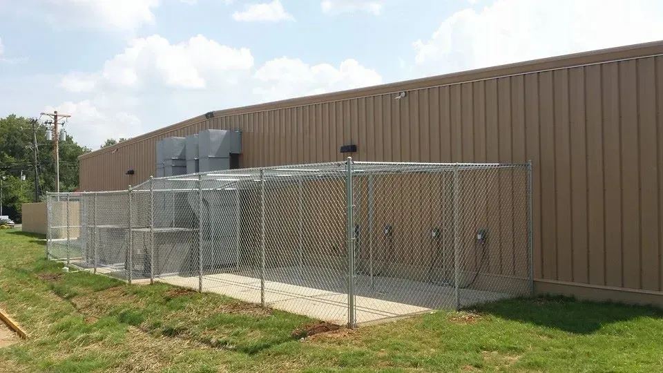 A chain link fence is surrounding a large building.