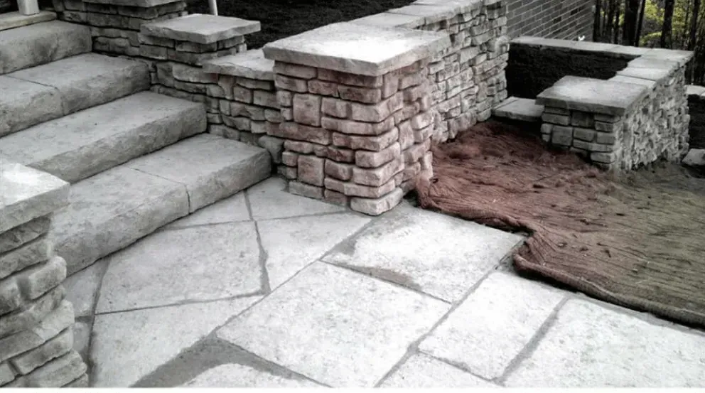 A stone patio with stairs and a stone wall
