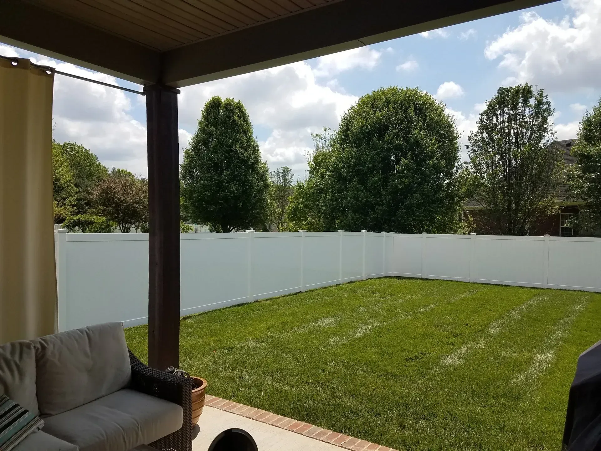 A backyard with a white fence and a couch