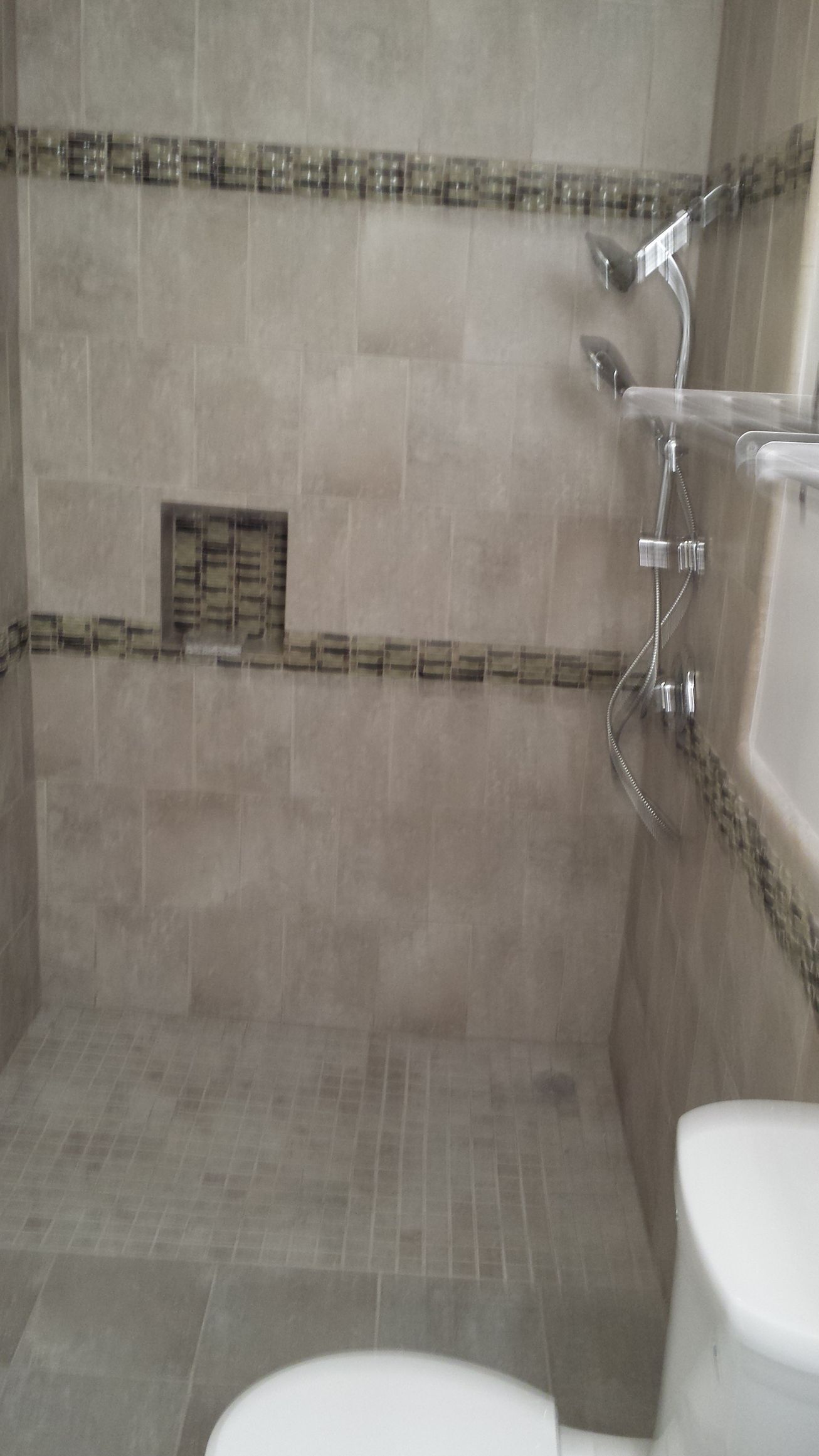 A bathroom with a toilet , shower and shower head.