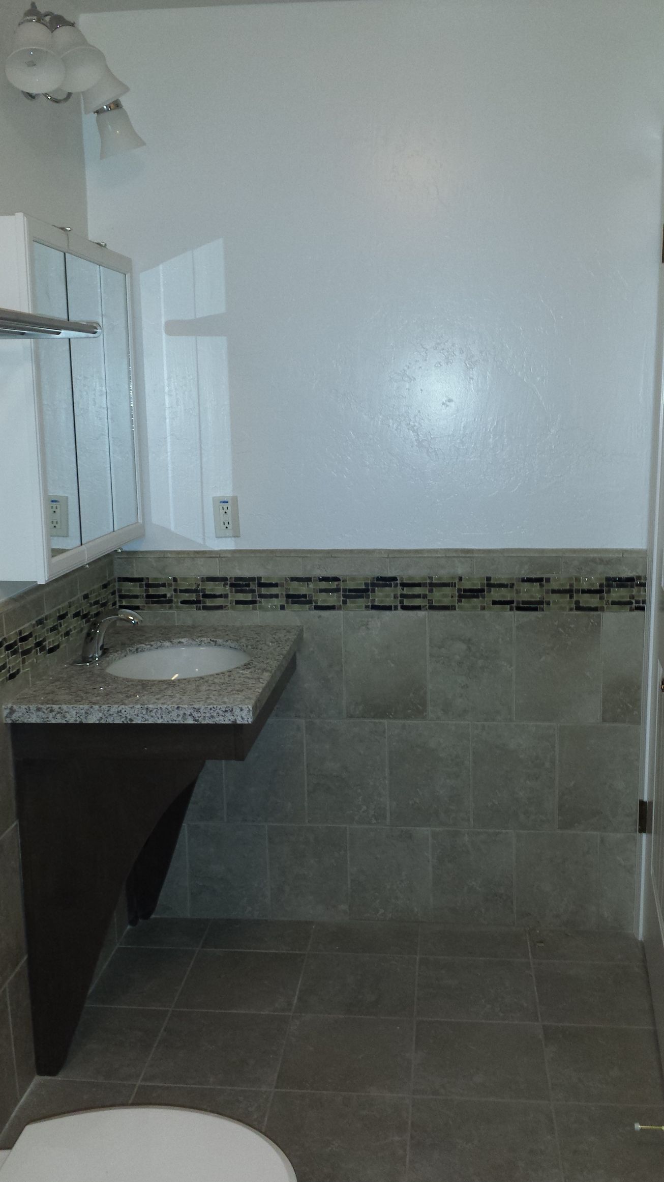 A bathroom with a sink , toilet and mirror.