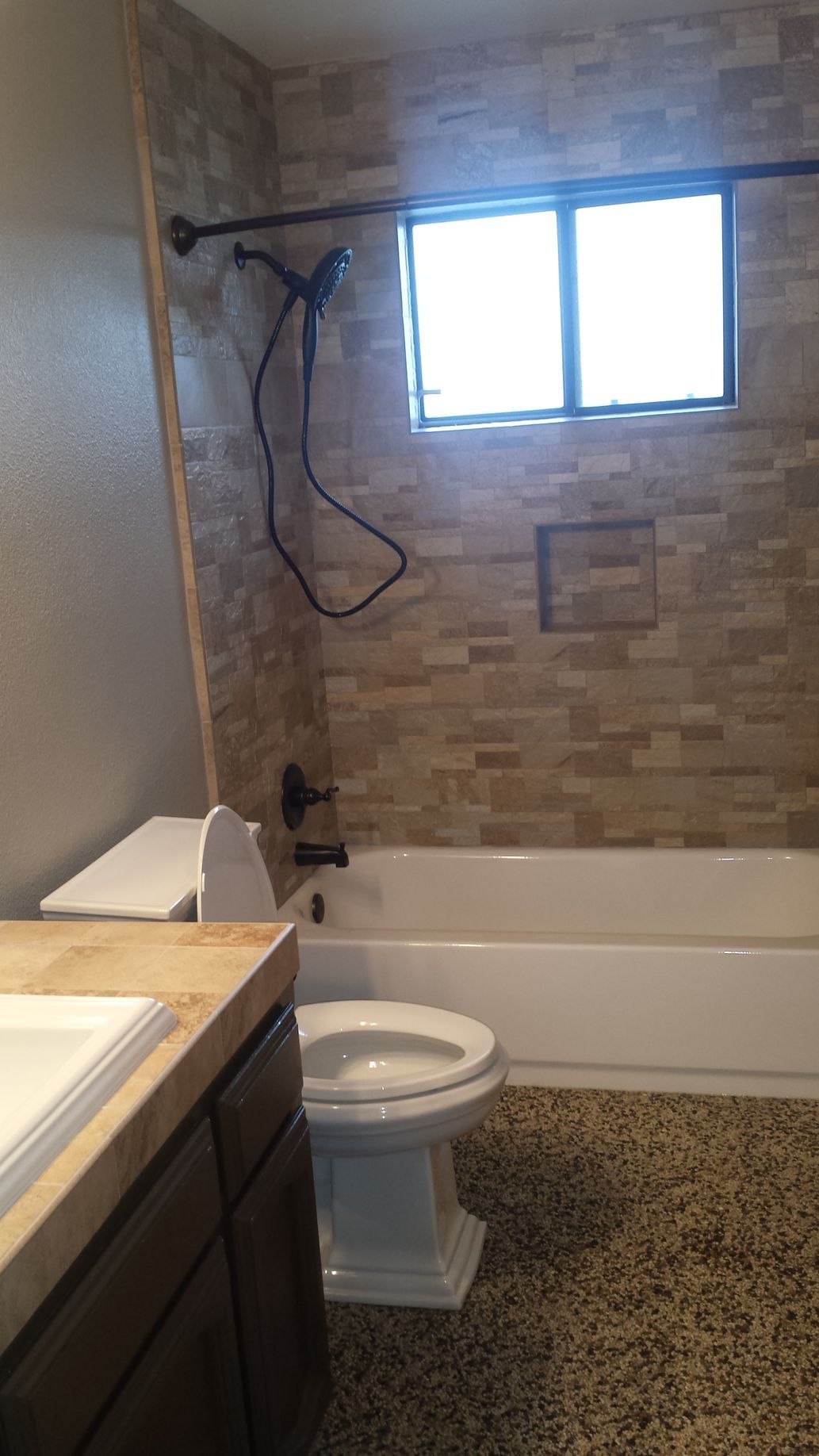 A bathroom with a toilet , tub , shower and window.